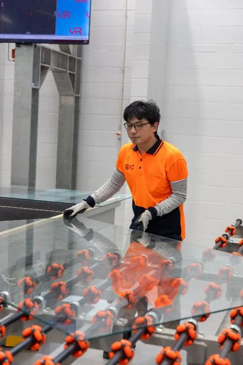 Worker handling glass in an industrial facility.  