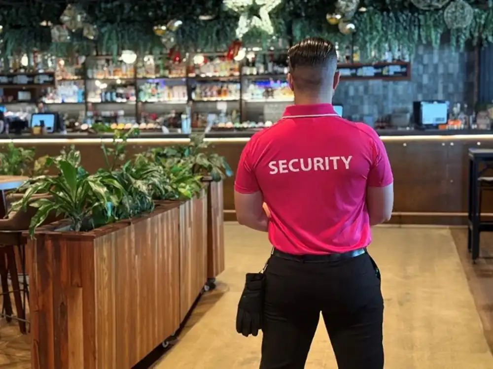 Security staff member in a pink shirt inside a venue.  