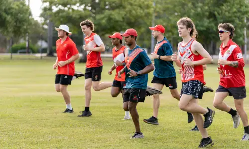Participants running together during a community sports training session on a grass field.