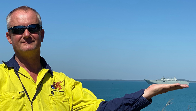 Man standing in front of ocean holding up a ship