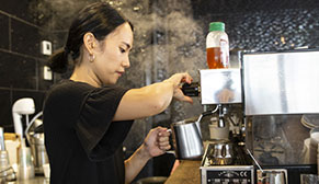 Person frothing milk on a coffee machine.